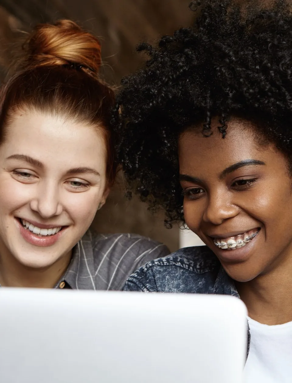 Duas estudantes sorrindo diante de um notebook